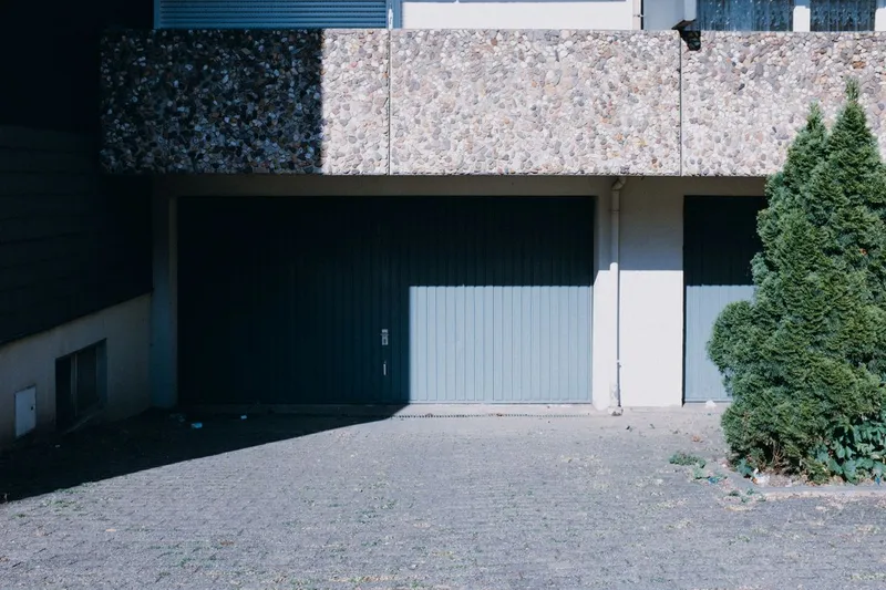 Two-car garage with closed double doors on a contemporary suburban house with a tree out front